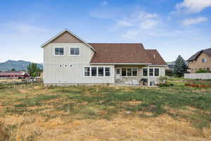 Back of house featuring board and batten siding, roof with shingles, a mountain view, and a patio area