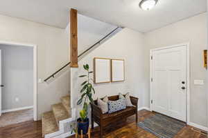 Foyer entrance featuring stairway, wood finished floors, and a textured ceiling