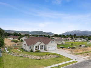 View of front of house with driveway, a mountain view, a front yard, board and batten siding, and roof with shingles