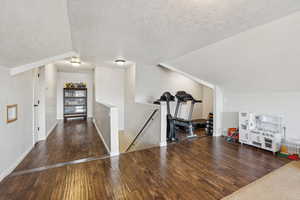 Bonus room featuring a textured ceiling, wood finished floors, and vaulted ceiling