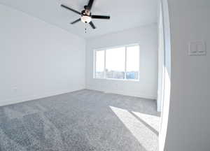 Carpeted empty room with ceiling fan and baseboards
