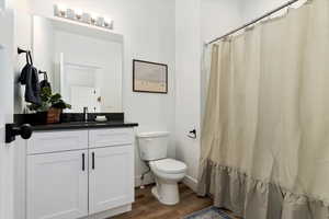 Bathroom with wood finished floors, vanity, and a shower with shower curtain