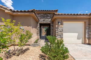View of exterior entry featuring stone siding, an attached garage, and stucco siding