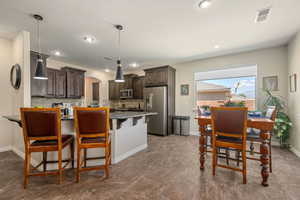 Kitchen featuring arched walkways, stainless steel appliances, dark brown cabinetry, backsplash, and a peninsula