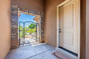 Property entrance featuring stucco siding, stone siding, and a gate