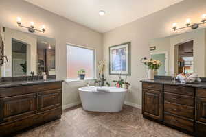 Bathroom featuring vanity, healthy amount of natural light, a soaking tub, and marble finish floors