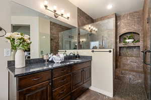 Full bathroom with tiled shower, double vanity, and tile patterned floors