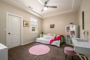Bedroom featuring carpet floors, a tray ceiling, and a ceiling fan
