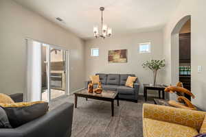 Living area with carpet flooring, arched walkways, and a chandelier