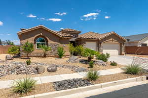 Mediterranean / spanish house with stone siding, a garage, a tile roof, stucco siding, and driveway