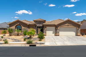 Mediterranean / spanish-style home with stone siding, an attached garage, driveway, stucco siding, and a tiled roof