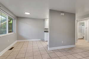 Unfurnished room featuring light tile patterned flooring and baseboards