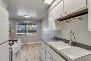 Kitchen featuring white appliances, white cabinets, and light tile patterned floors