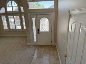 Foyer entrance with light stone finish floors and light colored carpet