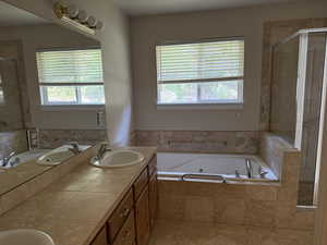 Full primary bath featuring plenty of natural light, double vanity, and a shower stall