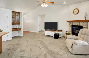 Carpeted living area featuring a ceiling fan, and brick fireplace.