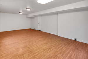 Another view of  basement -  future kitchen  that is plumbed for kitchen  sink, outlets installed for stove and laundry room. light wood-style floors and baseboards.