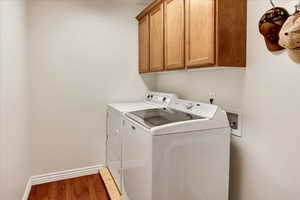 Laundry room featuring walnut cabinet space, independent washer and dryer, and wood finished floors.