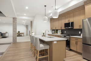 Kitchen featuring appliances with stainless steel finishes, open floor plan, recessed lighting, light countertops, and a kitchen island with sink