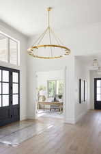 Foyer with a chandelier, wood-type flooring, and crown molding