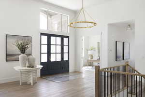 Entryway with wood finished floors, a chandelier, a high ceiling, and ornamental molding