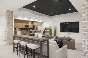 Living area with a tray ceiling, decorative columns, light colored carpet, and recessed lighting