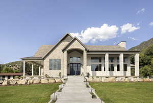 View of front facade with french doors, stone siding, a front yard, and a chimney