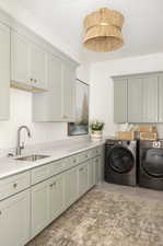 Laundry room featuring cabinet space, washer and dryer, and light tile patterned floors