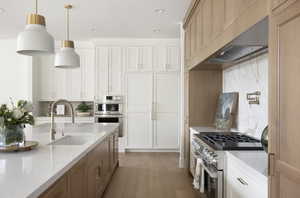 Kitchen with stainless steel appliances, light wood-type flooring, light stone countertops, decorative light fixtures, and recessed lighting