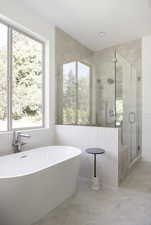 Full bath featuring a soaking tub, a shower stall, and tile walls