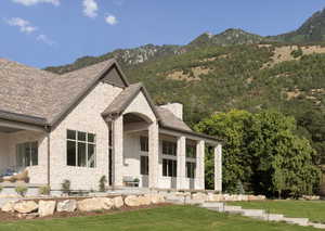 View of front facade featuring stone siding, a front lawn, a porch, and a chimney