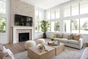 Living area featuring wood finished floors, a fireplace, and a towering ceiling
