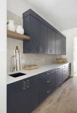 Kitchen featuring open shelves, light wood-style floors, light countertops, modern cabinets, and backsplash