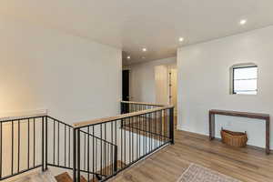 Stairway with wood finished floors and recessed lighting
