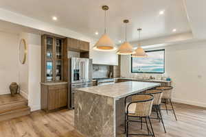 Kitchen featuring high quality fridge, light wood-type flooring, a center island, a kitchen breakfast bar, and recessed lighting