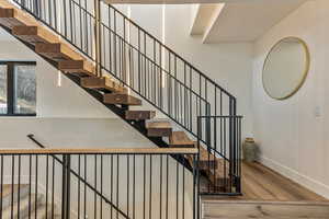Stairway with wood finished floors and baseboards