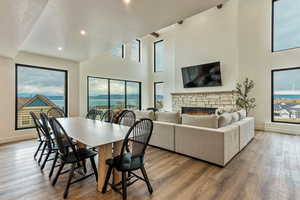 Dining room featuring a stone fireplace, wood finished floors, a textured ceiling, recessed lighting, and a towering ceiling