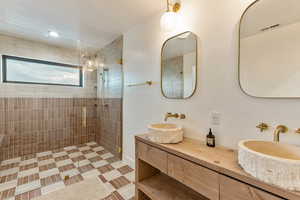 Bathroom featuring tiled shower and double vanity