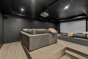 Carpeted cinema with recessed lighting and a tray ceiling