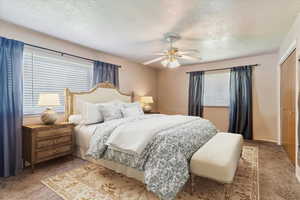 Carpeted bedroom with a textured ceiling and a ceiling fan
