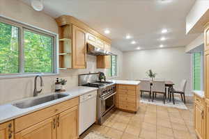 Kitchen with light brown cabinets, light countertops, backsplash, high end stainless steel range, and recessed lighting