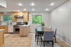 Kitchen with light countertops, high end stainless steel range oven, decorative backsplash, dishwasher, and ventilation hood