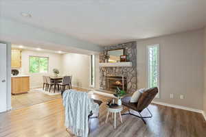 Living room featuring light wood-type flooring, a stone fireplace, and recessed lighting
