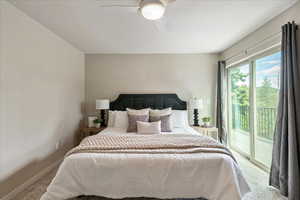 Primary bedroom featuring access to outside, carpet, and a ceiling fan