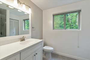 Bathroom featuring vanity, tiled shower, stone finish floors, and a closet