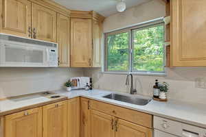 Kitchen featuring white appliances, backsplash, and light countertops