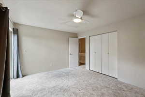 Unfurnished bedroom with carpet, a ceiling fan, and a closet