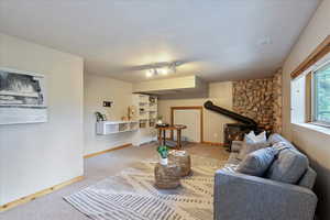 Carpeted living room with a wood stove and baseboards