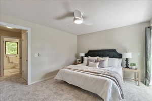 Primary carpeted bedroom with ceiling fan and connected bathroom