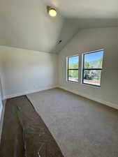 Additional living space with carpet flooring and lofted ceiling
